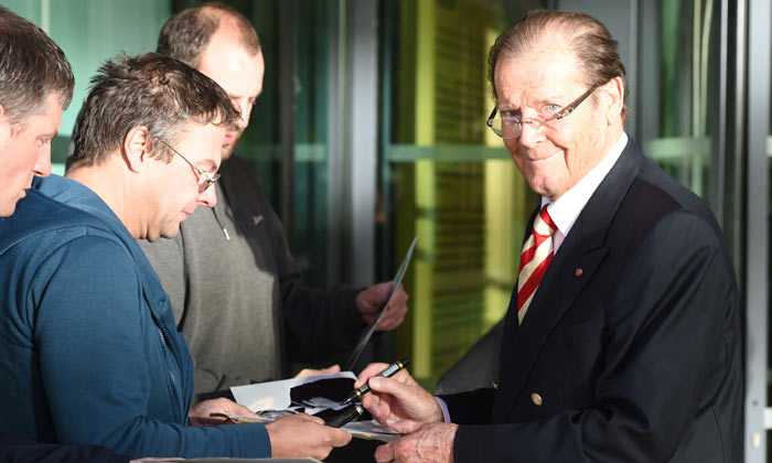 Ever the gent, Sir Roger Moore stops to sign autographs in 2015