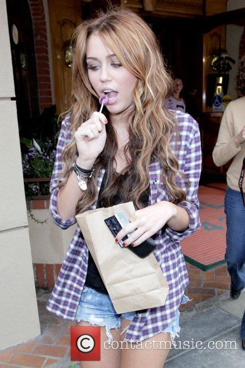 Miley Cyrus sucking on a lollipop while walking