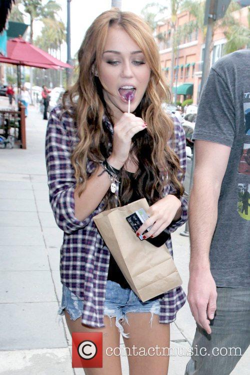 Miley Cyrus sucking on a lollipop while walking