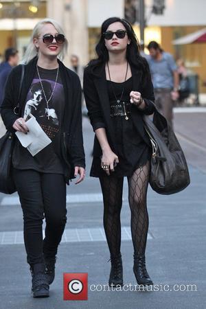 Demi Lovato wearing an all black ensemble and carrying a large handbag