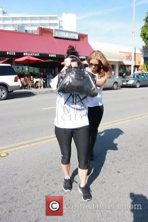 Picture Kim Kardashian in no makeup and workout clothes holds her bag in 