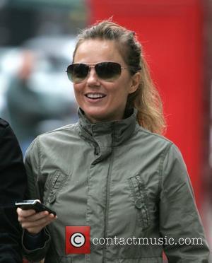 Geri Halliwell smiling and using a mobile device while out and about with her daughter in London.  Lodnon, England...