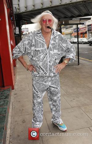 Sir Jimmy Savile poses at Gold's Factory Outlet where he wore a suit to help promote the store's deal of...