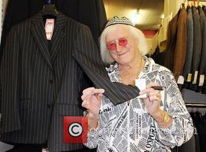 Sir Jimmy Savile checks out a suit at Gold's Factory Outlet where he wore a suit to help promote the...
