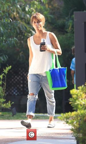 A make up free Halle Berry seen wearing a white vest top with ripped jeans while out and about in...